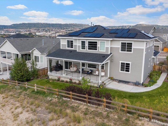 rear view of property with solar panels and a deck