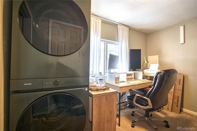 office featuring estacked washer and dryer, carpet flooring, a textured ceiling, a textured wall, and baseboards