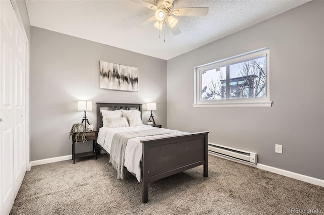 bedroom with a baseboard heating unit, a textured ceiling, carpet, and baseboards