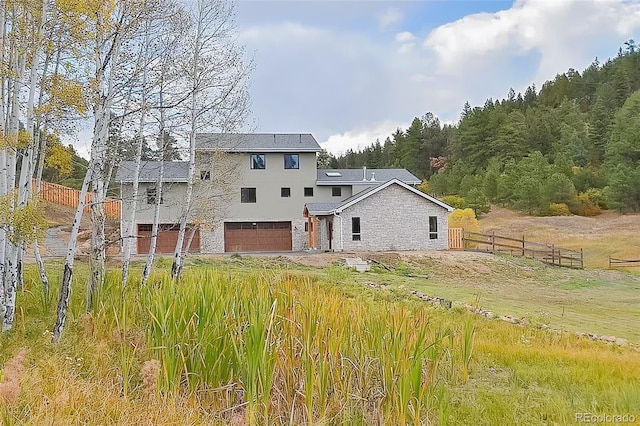 back of house featuring fence, an attached garage, and stucco siding