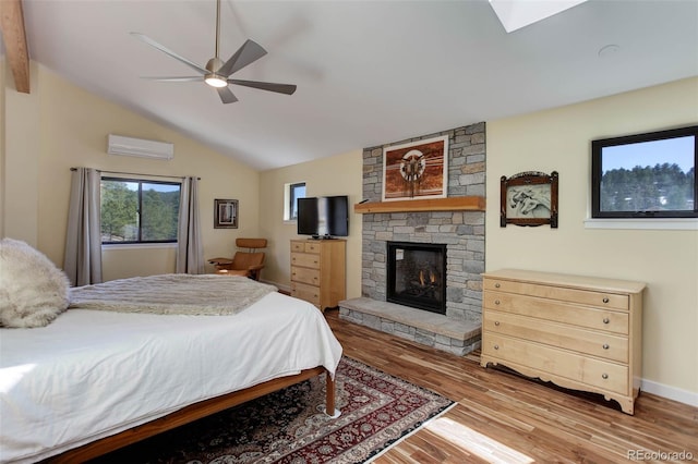 bedroom featuring lofted ceiling, ceiling fan, a fireplace, wood finished floors, and a wall mounted AC