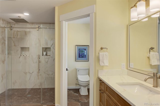 bathroom with toilet, a stall shower, vanity, and baseboards