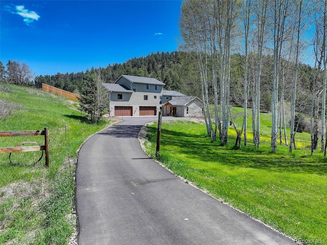 20101 Spring Gulch Rd, Morrison, CO 80465 - view of front facade with stucco siding, an attached garage, a view of trees, and asphalt driveway