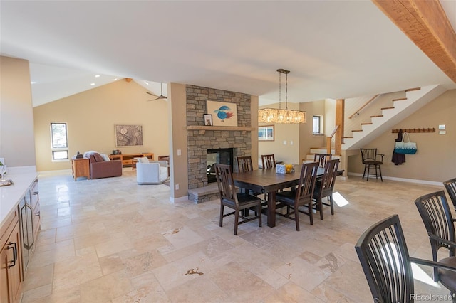 20101 Spring Gulch Rd, Morrison, CO 80465 - dining space featuring stairs, a fireplace, baseboards, light stone finish floors, and vaulted ceiling