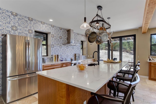 20101 Spring Gulch Rd, Morrison, CO 80465 - kitchen featuring stainless steel appliances, wall chimney exhaust hood, a sink, decorative backsplash, and a breakfast bar area