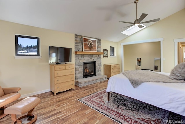 20101 Spring Gulch Rd, Morrison, CO 80465 - bedroom with wood finished floors, a stone fireplace, a skylight, vaulted ceiling, and baseboards