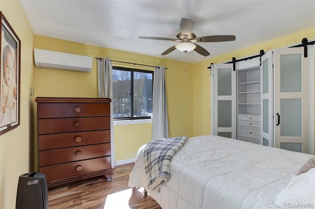 20101 Spring Gulch Rd, Morrison, CO 80465 - bedroom with a wall unit AC, a barn door, wood finished floors, and baseboards