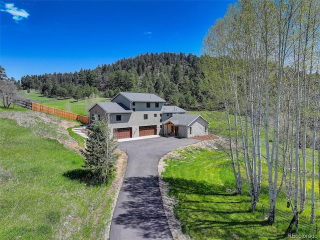 20101 Spring Gulch Rd, Morrison, CO 80465 - view of front of home with a wooded view, stucco siding, driveway, and an attached garage
