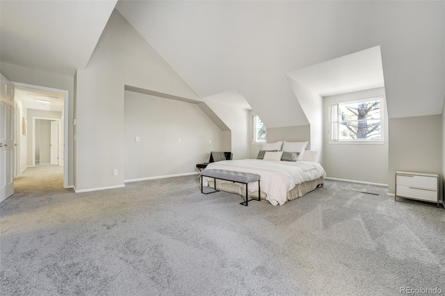 carpeted bedroom with vaulted ceiling and baseboards