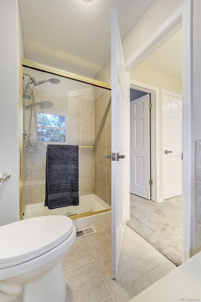 full bath with a stall shower, tile patterned flooring, and toilet