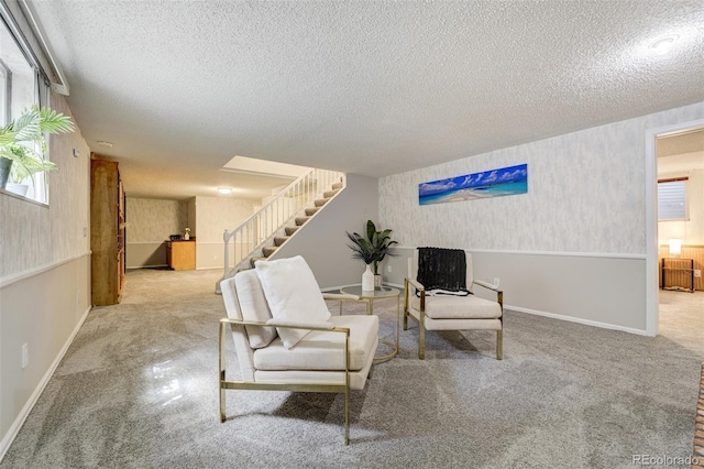 sitting room with a textured ceiling, carpet, stairway, and baseboards