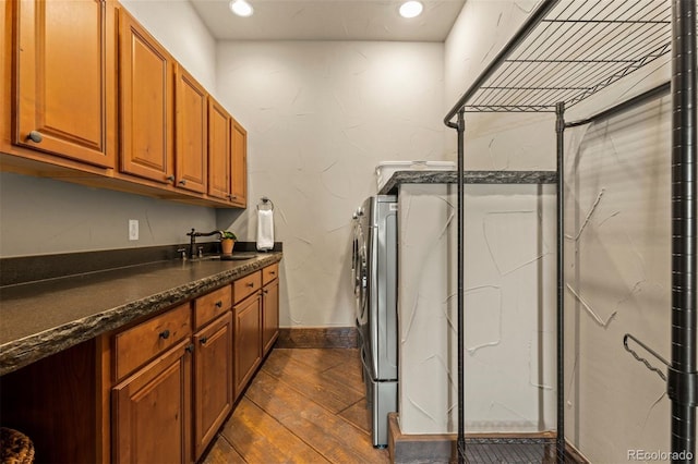 laundry area featuring cabinets, dark hardwood / wood-style flooring, sink, and washer and clothes dryer