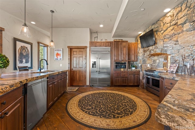 kitchen featuring high end appliances, dark hardwood / wood-style flooring, light stone countertops, and sink