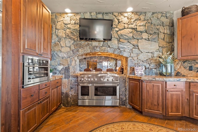142 Outpost Ln, Evergreen, CO 80439 - kitchen with appliances with stainless steel finishes, dark wood-style floors, light stone counters, and brown cabinetry