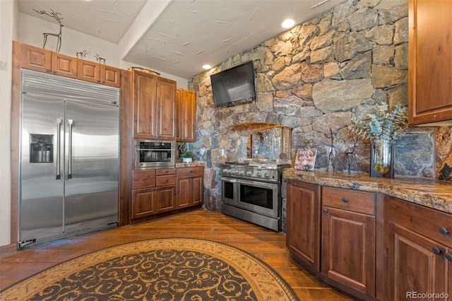 142 Outpost Ln, Evergreen, CO 80439 - kitchen with high end appliances, dark wood-style floors, brown cabinets, and dark stone counters