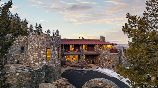 142 Outpost Ln, Evergreen, CO 80439 - rear view of property featuring a balcony, stone siding, and a patio area