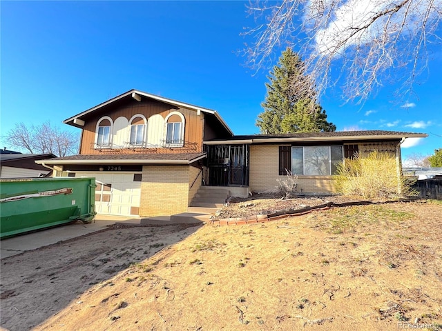 tri-level home featuring an attached garage, brick siding, and driveway