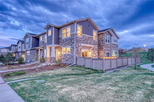 exterior space featuring a lawn, fence, and stone siding