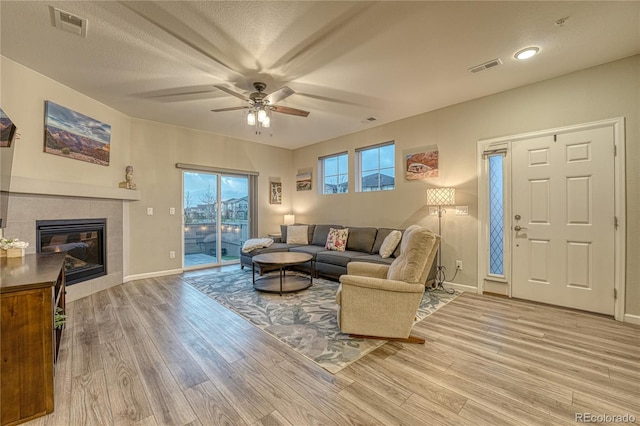living room with a ceiling fan, baseboards, visible vents, and light wood-style floors