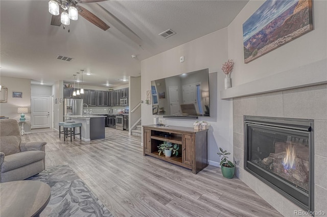 living room with visible vents, a ceiling fan, and light wood-type flooring
