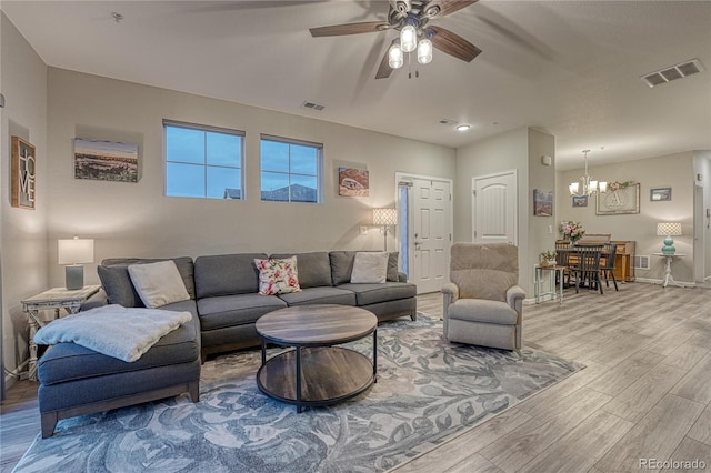 living area with visible vents, baseboards, ceiling fan with notable chandelier, and wood finished floors