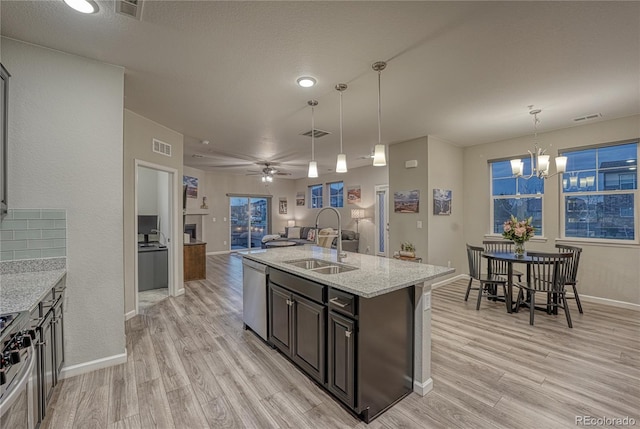 kitchen with a sink, stainless steel appliances, light wood-style flooring, and open floor plan