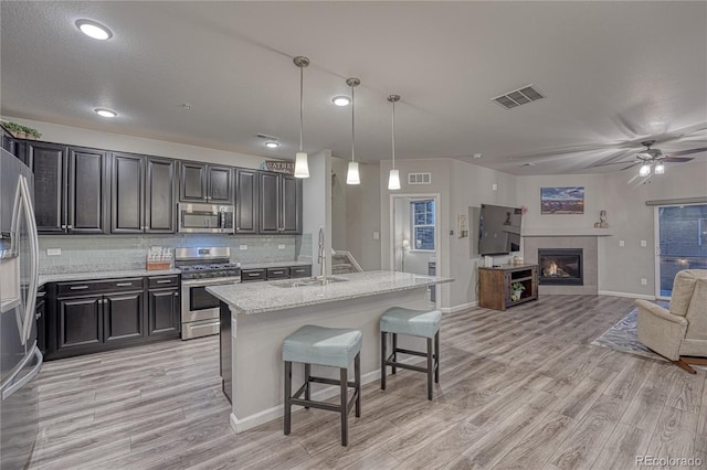 kitchen featuring a sink, light wood-style floors, stainless steel appliances, and visible vents