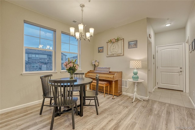 dining room featuring baseboards, light wood-style flooring, a notable chandelier, and visible vents