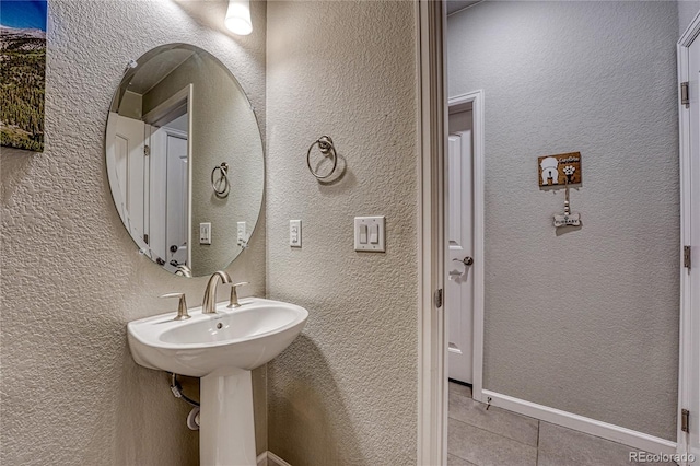 bathroom featuring tile patterned floors and a textured wall