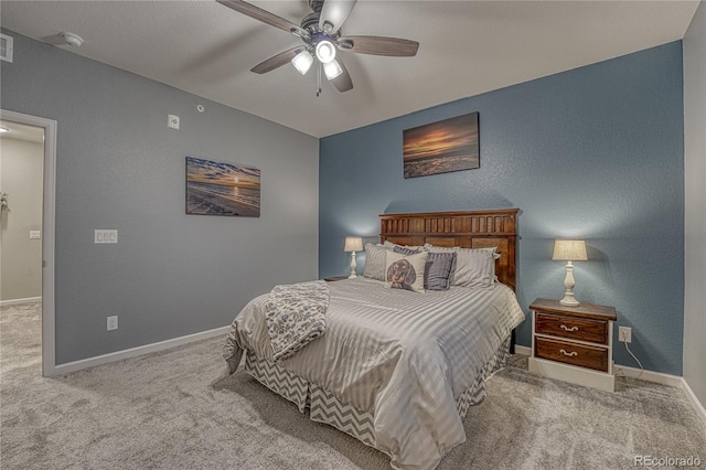 carpeted bedroom with visible vents, a ceiling fan, baseboards, and a textured wall