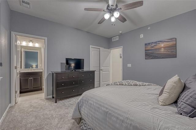 bedroom with visible vents, baseboards, ensuite bath, and light carpet