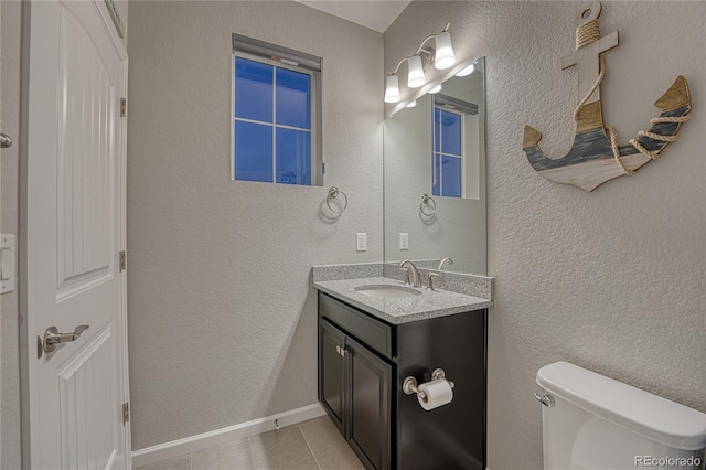 bathroom featuring toilet, a textured wall, tile patterned flooring, and vanity