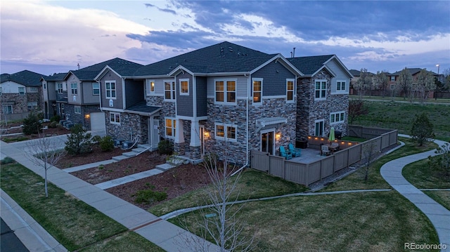 view of property featuring a residential view, fence, a front yard, and stone siding