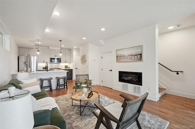 1238 N Tennyson St, Denver, CO 80204 - living area with stairway, light wood-type flooring, a glass covered fireplace, and recessed lighting