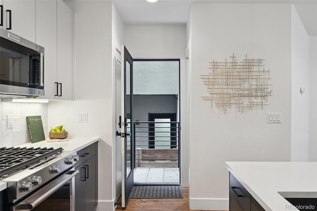 1238 N Tennyson St, Denver, CO 80204 - kitchen with wood finished floors, light countertops, white cabinets, baseboards, and appliances with stainless steel finishes