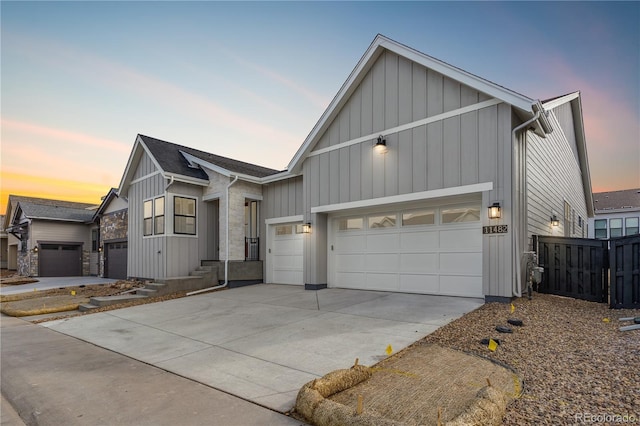 modern farmhouse with board and batten siding, fence, a garage, and concrete driveway