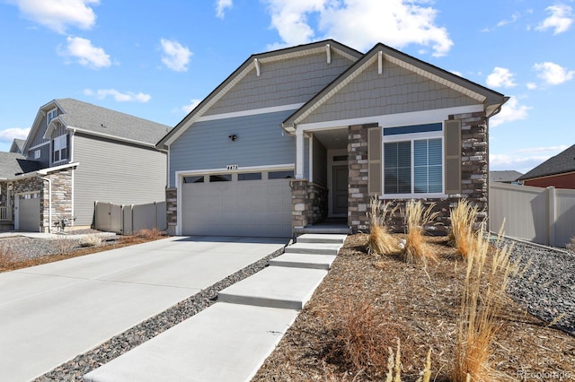 craftsman-style home featuring a garage, stone siding, concrete driveway, and fence