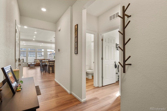 hallway with recessed lighting, visible vents, light wood-style flooring, and baseboards