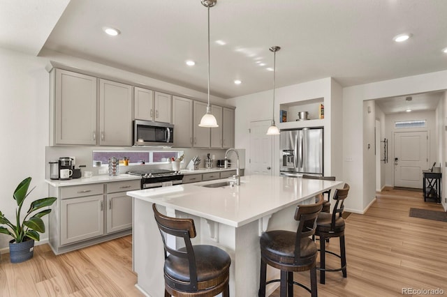 kitchen featuring gray cabinets, appliances with stainless steel finishes, light wood-style flooring, and a sink