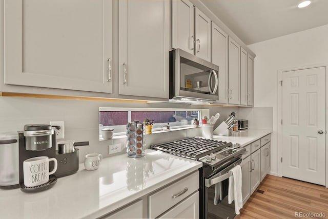 kitchen featuring decorative backsplash, appliances with stainless steel finishes, light countertops, and light wood finished floors