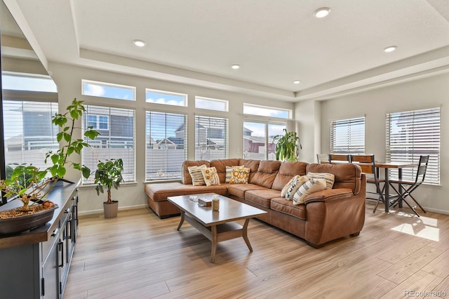 living room with a tray ceiling, light wood-style flooring, recessed lighting, and baseboards