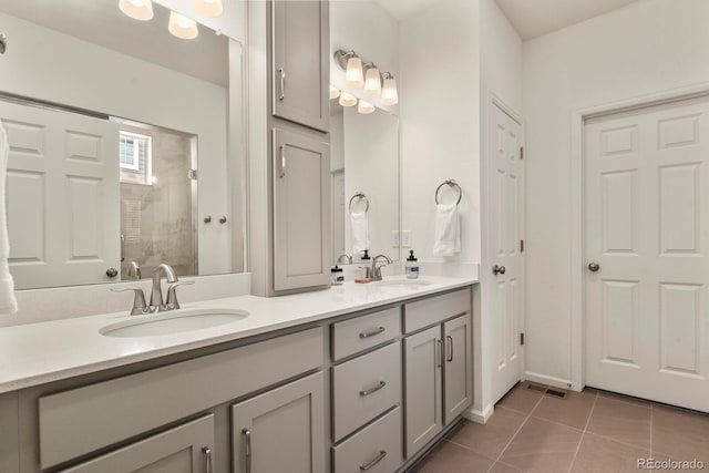 full bathroom featuring tile patterned flooring, tiled shower, visible vents, and a sink