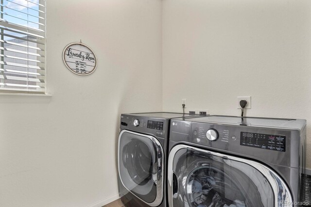 clothes washing area with laundry area, washer and dryer, and baseboards