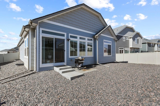 rear view of property with entry steps and a fenced backyard