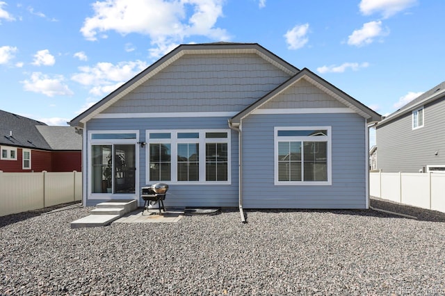 rear view of house with a fenced backyard and entry steps