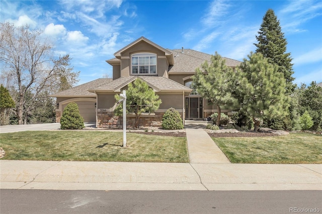view of front facade featuring a front yard, stucco siding, a shingled roof, and driveway