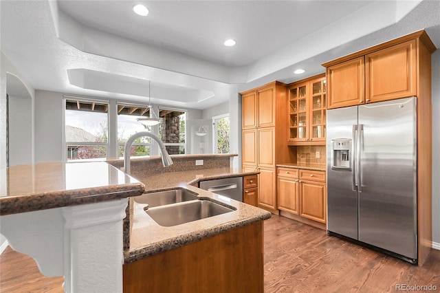kitchen featuring wood finished floors, a sink, stone countertops, a kitchen island with sink, and appliances with stainless steel finishes