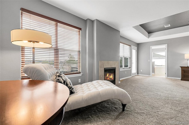 bedroom featuring carpet, connected bathroom, a tiled fireplace, visible vents, and baseboards