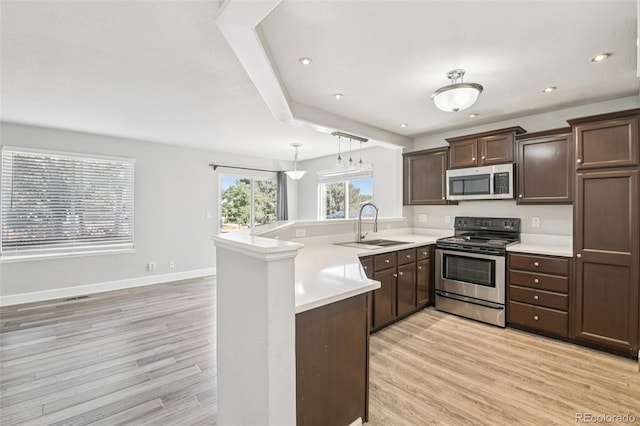 2125 E 103rd Ave, Thornton, CO 80229 - kitchen with stainless steel appliances, a peninsula, light wood-style flooring, dark brown cabinetry, and light countertops