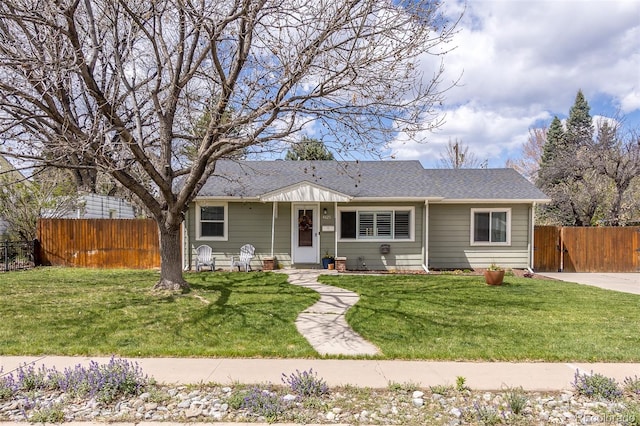 view of front of home featuring fence, a shingled roof, and a front yard